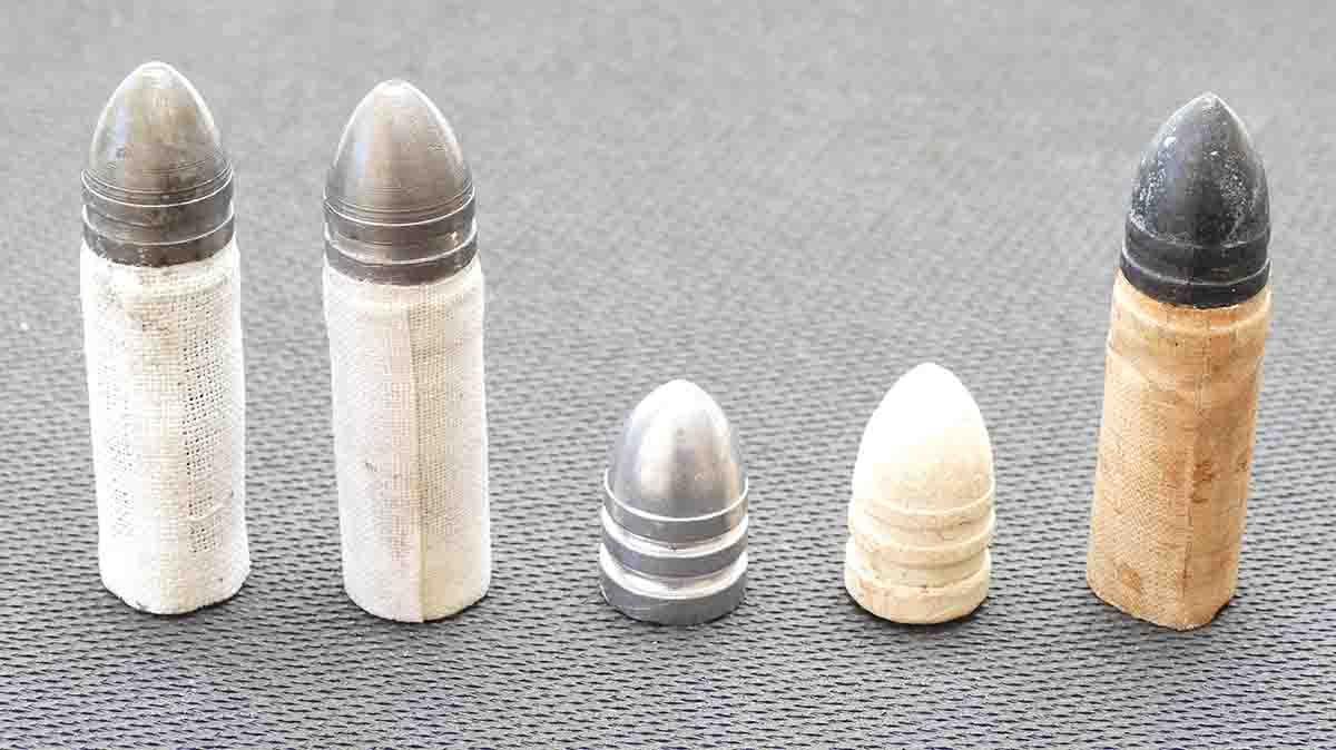 On the left is our reproduction a linen cartridge, followed by our reproduction cotton cartridge, and the naked bullet used in the test. Next is an original Sharps flat-base bullet and an original Sharps linen cartridge. The linen was glued onto the base of the bullet and often “choked” into the bottom grease groove (sans grease) for even more durability, as shown here.